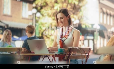 Dipendente dell'azienda che lavora al suo progetto in remoto da un Cafe Space all'aperto. Manager che comunica con partner aziendali e colleghi online. Donna che scrive e-mail e rapporti di lavoro Foto Stock
