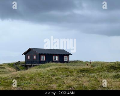 Una casa solitaria e pittoresca in stile danese su un prato sotto il cielo nuvoloso scuro prima della pioggia, Skagen, sulla strada per capo Grenen. Foto Stock