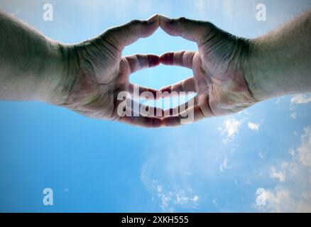 mans mani alzate con le dita che toccano il cielo blu del norfolk inghilterra Foto Stock