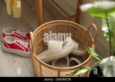 Cestino con pantofole per gli ospiti e scarpe da ginnastica all'ingresso di casa Foto Stock