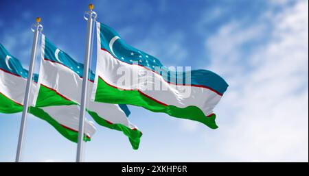 Tre bandiere nazionali dell'Uzbekistan sventolano in una giornata limpida. Paese sovrano dell'Asia centrale. rendering illustrazione 3d. Tessuto ondulato. Messa a fuoco selettiva. Foto Stock