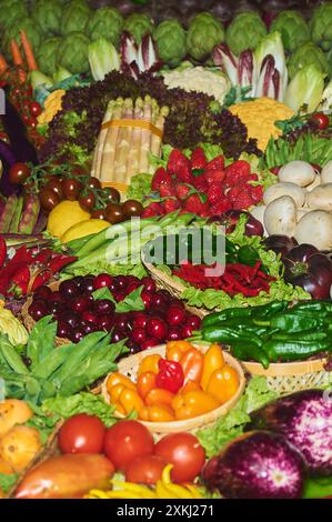 Una variopinta selezione di prodotti agricoli freschi, tra cui carciofi verdi, melanzane viola, verdi a foglia verde, fragole rosse, funghi bianchi e gialli Foto Stock