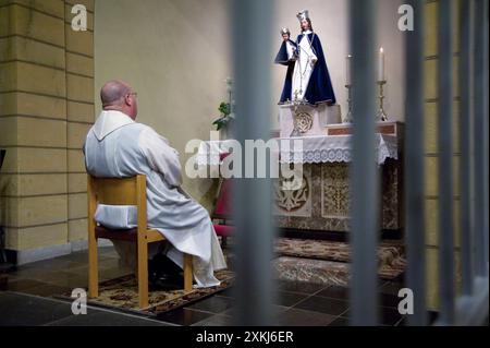 Ritratto Pastore e sacerdote Pastore e sacerdote della Chiesa Cattolica Romana che conduce il suo gregge in una preghiera di Rosario e Paternoster durante una messa serale all'interno della sua Chiesa. Hulsberg, Paesi Bassi. Hulsberg Katholieke Kerk - Dorpskerk Limburg - Zuid Limburg Nederland Copyright: XGuidoxKoppesxPhotox Foto Stock