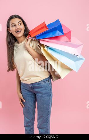 Donna stupita che indossa T-shirt casual e jeans in visita a una boutique alla moda con borse per lo shopping Foto Stock