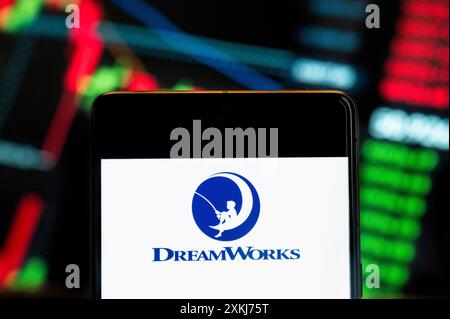 In questa illustrazione fotografica, il logo DreamWorks dell'etichetta di produzione cinematografica americana è stato visualizzato su uno smartphone con un grafico dell'indice di borsa economica sullo sfondo. Foto Stock