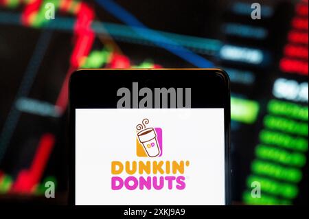 Cina. 21 giugno 2024. In questa illustrazione fotografica, il logo Dunkin' Donuts, catena multinazionale americana di caffè e snack, visualizzato su uno smartphone con un grafico dell'indice di borsa economica sullo sfondo. (Credit Image: © Budrul Chukrut/SOPA Images via ZUMA Press Wire) SOLO PER USO EDITORIALE! Non per USO commerciale! Foto Stock