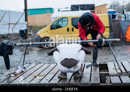 Fare una doccia migrante illegale eritreo nella giungla di Calais, lavando la sua voce in un punto d'acqua improvvisato. Calais, Francia. Calais The Jungle Nord pas de Calais Francia Copyright: XGuidoxKoppesxPhotox Foto Stock