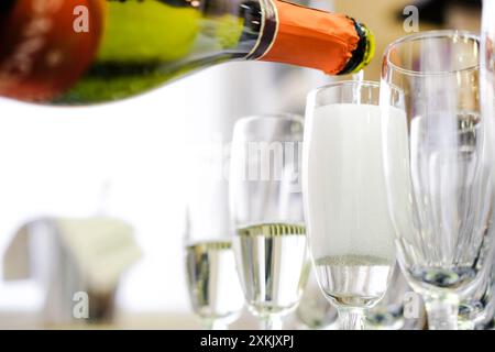 Primo piano del vino frizzante versato in bicchieri per flauto, catturando le bollicine effervescenti. Ripresa orizzontale. Foto Stock