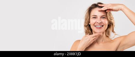 Concetto di Facebuilding. Felice bella donna di mezza età che tocca Chin, Forehead Foto Stock