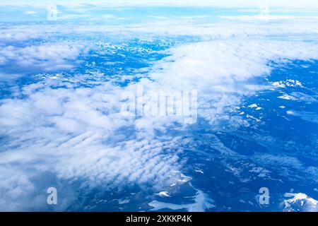 Vista panoramica del cielo dall'aeroplano, con soffici nuvole. il cielo è blu con nuvole e montagne sullo sfondo. Le nuvole sono soffici e bianche, e. Foto Stock