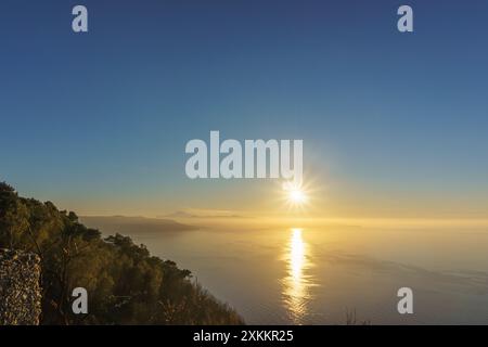 Baia mediterranea vista dal punto panoramico di Monte Sant'Elia durante il tramonto con fumo che sale dal vulcano attivo dell'Etna in Sicilia, Palmi, Calabria, Italia Foto Stock