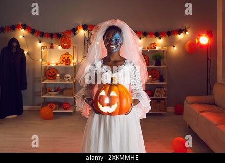 Ritratto di una giovane donna dalla pelle scura sorridente vestita da sposa morta alla festa di Halloween. Foto Stock