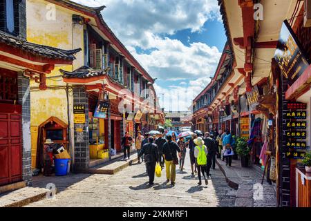 I turisti asiatici camminano per strada nella città vecchia di Lijiang Foto Stock