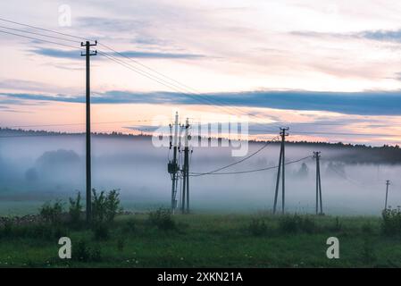 Pali elettrici su Un tramonto nebuloso su Un paesaggio rurale Foto Stock