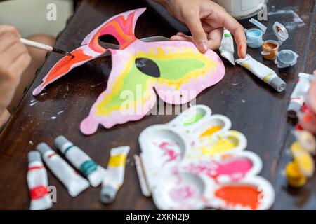 Una persona sta dipingendo una maschera a farfalla con una varietà di colori. Il processo di pittura è un'attività creativa e divertente che consente alla persona di esprimere Foto Stock