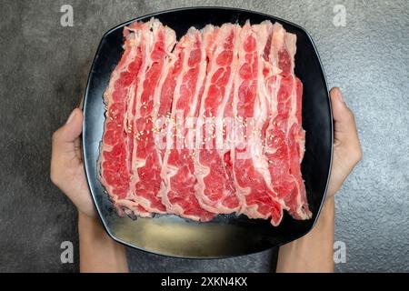 Una persona sta tenendo un piatto di carne con semi di sesamo sopra. La carne viene affettata e sistemata in modo da renderla appetitosa Foto Stock