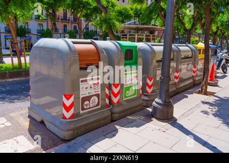 Tarragona, Spagna - 15 luglio 2024: Una serie di bidoni di riciclaggio colorati in una strada soleggiata di Tarragona. Foto Stock