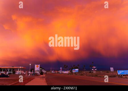 Baker, California - 15 aprile 2024: Le nuvole di lavanda dominano lo skyline della California al tramonto, proiettando un magico bagliore sulla stazione di servizio e sul bordo della strada Foto Stock