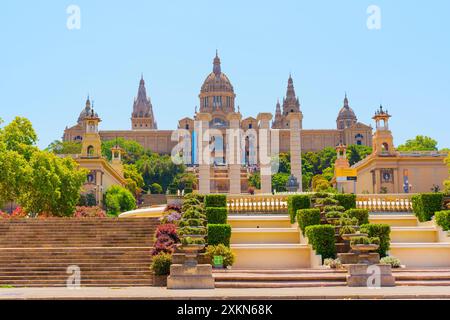 Barcellona, Spagna - 16 luglio 2024: Vivace giardino e scale che portano alla grande facciata del Palau Nacional. Foto Stock