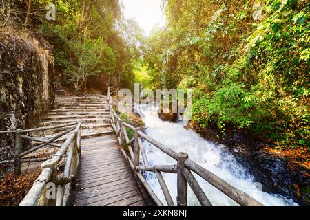 Passerella in legno e scale in pietra che conducono lungo il fiume di montagna Foto Stock