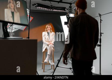 Una donna professionista sta registrando in uno studio con un equipaggio e apparecchiature di illuminazione Foto Stock