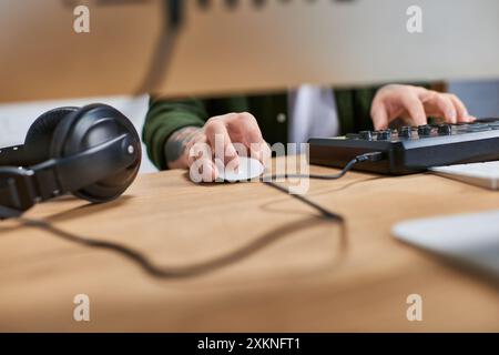 Un primo piano di un bel asiatico che usa un controller Midi in uno studio. Foto Stock