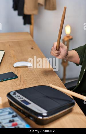 Un uomo asiatico suona la batteria in un ambiente informale, mostrando il suo talento musicale. Foto Stock