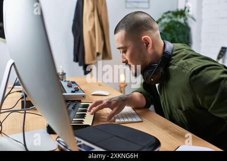 Un bell'uomo asiatico, un polistrumentista, si vede nel suo studio suonare una tastiera. Foto Stock