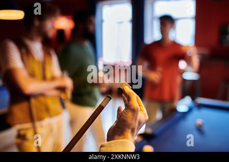 Un gruppo di amici gioca casualmente a biliardo in una stanza poco illuminata. Foto Stock