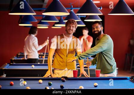 Gli amici giocano a biliardo insieme in un ambiente informale, mostrando una serata divertente e divertente. Foto Stock