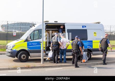 Londra, Regno Unito. 24 LUGLIO 2024. La polizia carica un attivista arrestato sul retro di un furgone della polizia mentre Just Stop Oil tentava di violare il perimetro dell'aeroporto di Heathrow, gli attivisti non sono stati in grado di accedere alla pista e la polizia metropolitana ha confermato che 9 sono stati arrestati. A tre giornalisti, me compreso, è stato detto di non fotografare a causa di leggi aeroportuali, a seguito di una chiamata alla NUJ di Londra, i fotografi sono stati finalmente autorizzati a scattare una volta che la maggior parte dell'azione si era conclusa. Credito Milo Chandler/Alamy Live News Foto Stock