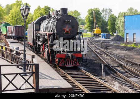 Il treno passeggeri rétro con locomotiva a vapore nera dell'URSS Times è vicino alla piattaforma della stazione ferroviaria centrale di Sortavala in un'estate soleggiata Foto Stock