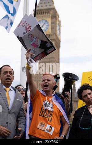 Parliament Square, Londra, Regno Unito. 24 luglio 2024. I parenti degli ostaggi rapiti da Israele il 7/10 2023, si uniscono all'artista Benzi Brofman, mentre dipinge una tela in un appello al neo eletto Partito Laburista per dare priorità al loro ritorno sicuro. Yair Keshet (zio di Yarden) - The Bibas Family: Yarden (35), Shiri (33), Ariel (4), Kfir (18 mesi) ospitato dal Forum UK degli ostaggi e delle famiglie scomparse. Amanda Rose/Alamy Live News Foto Stock