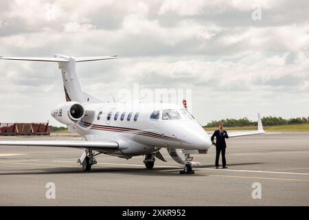 NETJETS pilota in piedi accanto a un jet Embraer Phenom 300E. Foto Stock