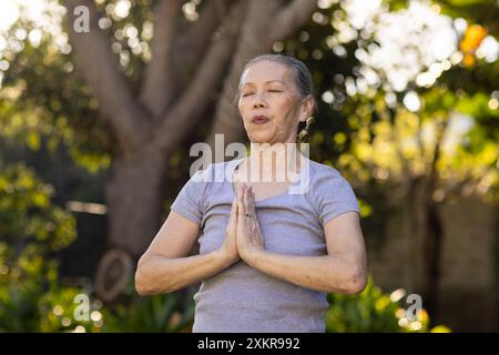 Pratica yoga, donna asiatica anziana che medita all'aperto con le mani in posizione di preghiera Foto Stock