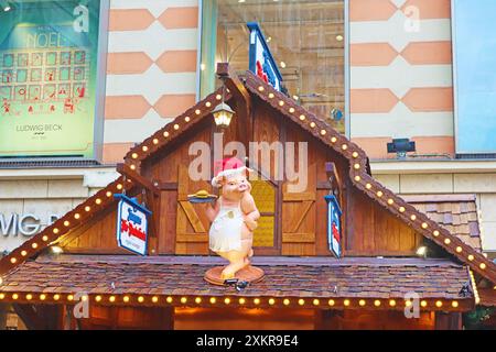 Monaco di Baviera, Germania - 20 dicembre 2023: Simpatica figura di maiale sul tetto del negozio sul mercatino di Natale in piazza Marienplatz Foto Stock