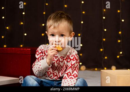 Un bambino carino che mangia pan di zenzero. Bambini di Natale Foto Stock