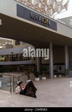 Siviglia, Spagna. 8 febbraio 2024 - persone sedute fuori dal centro commerciale Nervion Plaza a Siviglia, Spagna Foto Stock