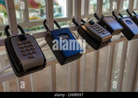 Cassette di sicurezza con chiave combinata montate su ringhiera bianca, primo piano Foto Stock