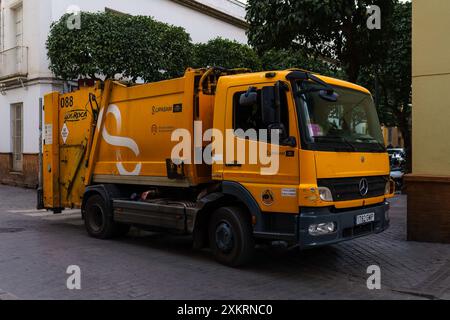 Siviglia, Spagna. 5 febbraio 2024 - camion della spazzatura giallo in una strada Foto Stock