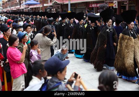 Butuo, la provincia cinese del Sichuan. 22 luglio 2024. La gente del posto vestita con i tradizionali costumi Yi sfilano su una strada durante il festival della torcia nella contea di Butuo, nella prefettura autonoma di Liangshan Yi, nella provincia del Sichuan, nel sud-ovest della Cina, 22 luglio 2024. I residenti in costumi tradizionali del gruppo etnico Yi hanno partecipato al festival delle torce di quattro giorni che si è svolto dal 21 al 24 luglio. Crediti: Jiang Hongjing/Xinhua/Alamy Live News Foto Stock