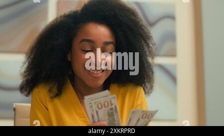 Felice gioiosa donna d'affari afroamericana ricca imprenditrice di successo che conta soldi dollari contanti salario credito finanziario sorridente Foto Stock