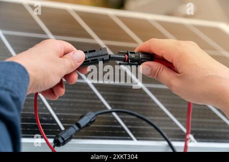 Primo piano delle mani del tecnico che collegano i connettori mc4 sul pannello solare. Energia rinnovabile e concetto di sostenibilità Foto Stock