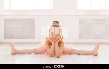 Piccola ballerina in spaccato sul pavimento, spazio di copia. Sorridente bambina sognando di diventare ballerina professionale, scuola di danza classica Foto Stock