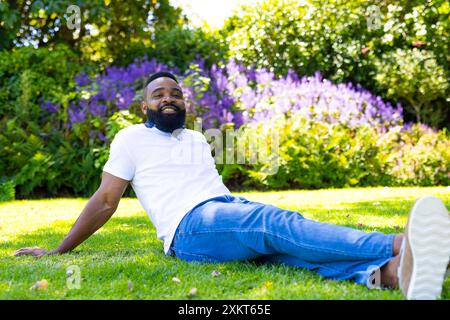 Rilassatevi sull'erba, uomo in camicia bianca e jeans godendosi una giornata di sole all'aperto Foto Stock