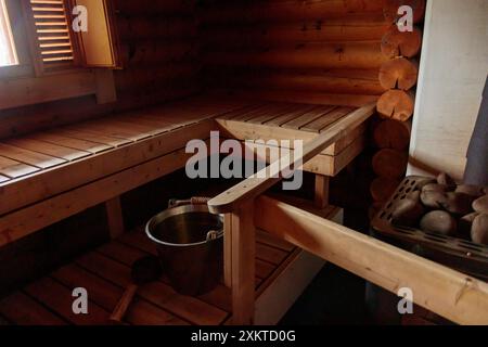 Sauna finlandese tradizionale in legno, accessorio nel bagno turco, riscaldamento sauna con pietre, secchio in acciaio inossidabile e vecchio mestolo, striscione con spazio per fotocopie. Foto Stock