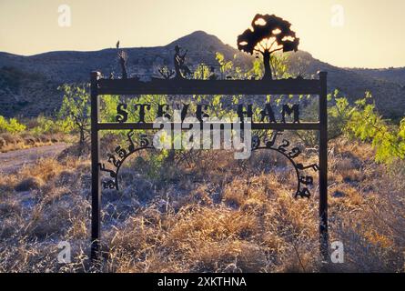 Insegna in ferro battuto per commemorare una persona all'ingresso del ranch al tramonto vicino a Pandale nella valle del fiume Pecos nella contea di Val Verde, Texas, USA Foto Stock