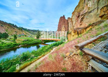 Smith Rock Red Cliffs e Ponte in legno sull'inclinazione aerea del fiume Foto Stock