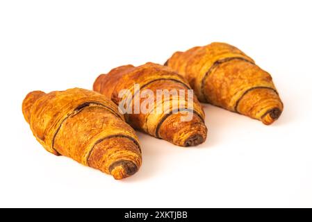 Un trio di croissant perfettamente cotti, marrone dorato e scaglie, sono impilati su uno sfondo bianco. I croissant hanno una leggera lucentezza e strati visibili Foto Stock