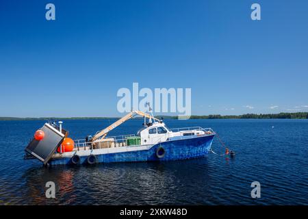 Piccolo peschereccio finlandese ancorato dietro la frangiflutti del lago Pohjois-Konnevesi, Finlandia Foto Stock